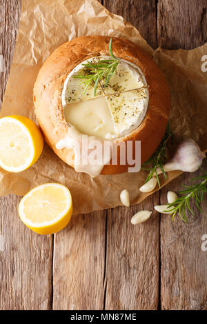 Fondue in einem Laib Brot aus geschmolzener Camembert Käse close-up auf einem Tisch. Vertikal oben Ansicht von oben Stockfoto