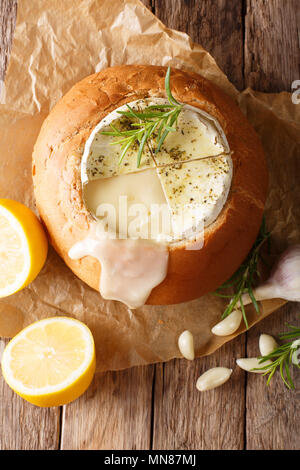 Geschmolzener Camembert in einem Laib Brot close-up auf einem Tisch. Vertikal oben Ansicht von oben Stockfoto