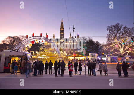 Blick über den Rathausplatz in Wien in der Weihnachtszeit. Menschen besuchen den Christkindlmarkt und deshalb warten an der Ampel die Straße überqueren Stockfoto