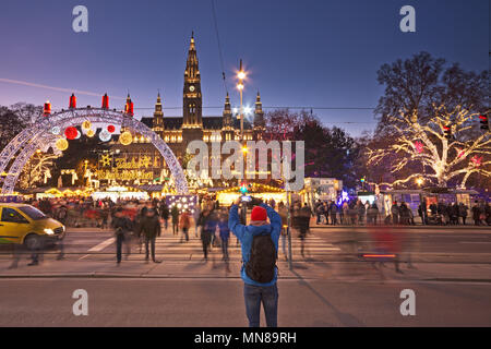 Blick über den Rathausplatz in Wien in der Weihnachtszeit. Tourist, der ein Bild der Landschaft. Menschen besuchen den Christkindlmarkt überqueren die Roa Stockfoto