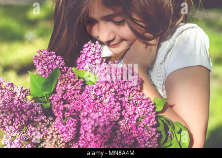 Kleines Mädchen mit Blumenstrauß aus Lila in Ihren Händen Stockfoto