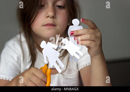 Trauriges kleines Mädchen mit Papier und Schere; Scheidung oder familiären Problemen Konzept Stockfoto