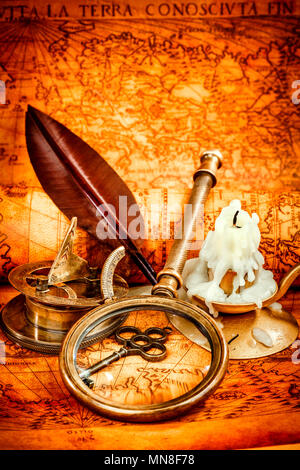 Vintage Kompass, Lupe, Taschenuhr, Federkiel, Spyglass liegen auf einer alten antiken Karte 1565 mit eine brennende Kerze. Vintage Stillleben. Stockfoto