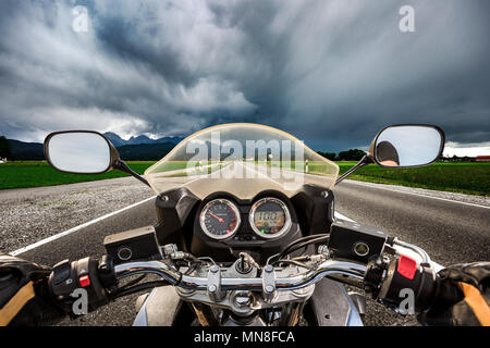 Biker auf einem Motorrad die Straße hinunter in ein Gewitter - Forggensee und Schwangau, Deutschland Bayern rast Stockfoto