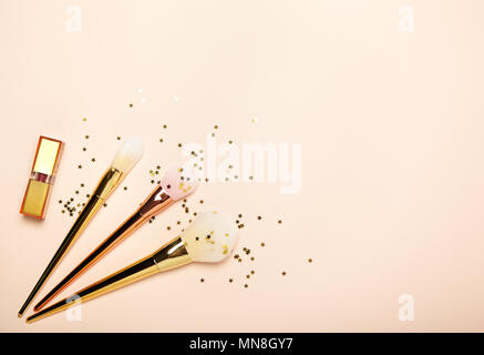 Modische Frauen&rsquo;s, Kosmetik und Accessoires. Falt legen. Make-up Lippenstift und Bürsten. Frauen Zubehör auf beigen Hintergrund Stockfoto