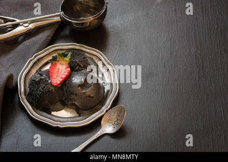 Schwarzes Eis in vintage Teller, garnieren frische Erdbeeren auf dem Schwarzen Brett. Platz für Text. Stockfoto