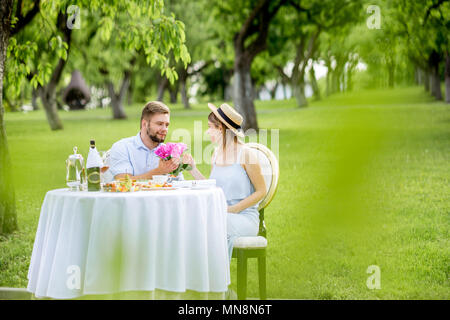 Junges Paar in romantisches Frühstück auf dem Gut bedient Tisch draußen sitzen in der schönen apple Garten Stockfoto