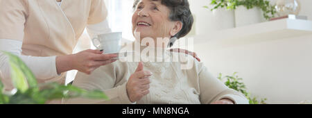 Lächelnd senior Frau danken, eine Krankenschwester für Kaffee bei einem Aufenthalt in einem Pflegeheim Haus Stockfoto