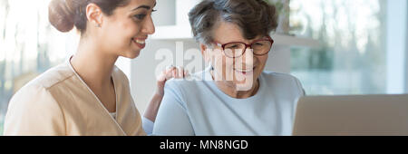 Freundlich freiwillig und gerne ältere Frau im Internet surfen, während Sie laptop Stockfoto