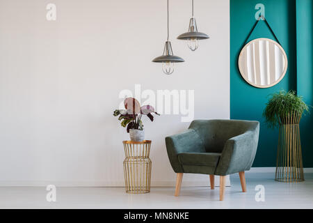 Helle Einrichtung in Weiß und Grün mit Sessel, Tisch mit Pflanzen, Lampen und Spiegel Stockfoto
