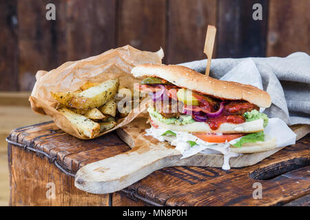 Hähnchen Schnitzel Sandwich mit Salat und hausgemachten Backofen Chips Stockfoto