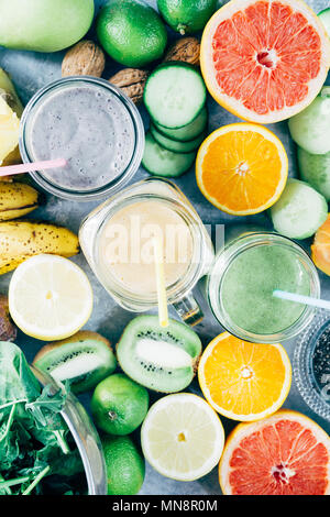 Gesunde grün, Mango, und blueberry Smoothie detox Drink in ein Glas von rohem Obst Zutaten, Banane, Ananas, Papaya, Gurken, Kohl, Spinat umgeben, Stockfoto