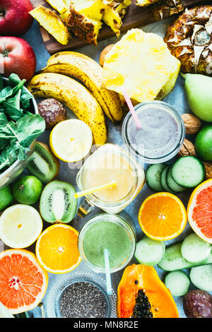 Gesunde grün, Mango, und blueberry Smoothie detox Drink in ein Glas von rohem Obst Zutaten, Banane, Ananas, Papaya, Gurken, Kohl, Spinat umgeben, Stockfoto