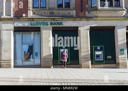 Eine Frau mit einem Geldautomaten zu Lloyds Bank im Vereinigten Königreich. Stockfoto