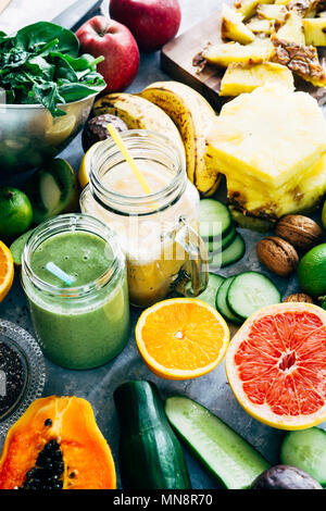 Gesunden grünen Smoothie detox Drink in ein Glas von rohem Obst Zutaten, Banane, Ananas, Papaya, Gurken, Kohl, Spinat umgeben, Stockfoto