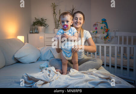 Portrait von Sleepy müde Junge Mutter Windeln Ihres Babys ändern bei Nacht Stockfoto