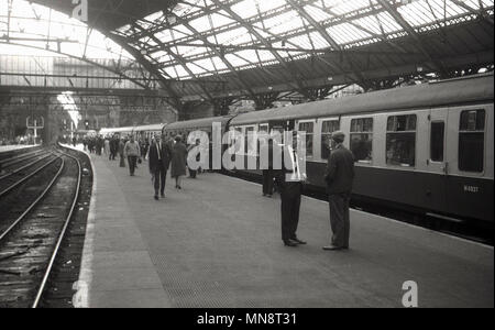 1960, historische Bild von der Liverpool Lime Street Station, die Passagiere auf der Plattform zu an Bord eines Waggons. Das war noch die Zeit der Dampflokomotiven, als in der Ferne zu sehen ist. Stockfoto