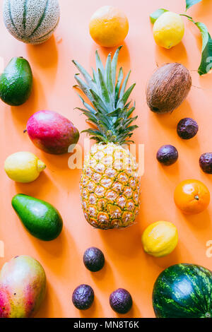 Organische exotische Früchte ein Hintergrundbild über eine Orange, Ansicht von oben, flach, Ananas, Wassermelone, Mango, Passionsfrucht Zuckermelone, Kokosnuss Stockfoto