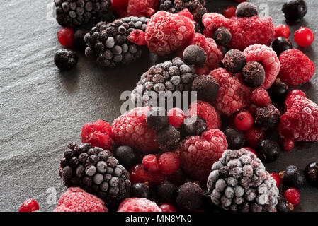 Gefrorene Sommer Beeren auf einem Schiefer Hintergrund, black Himbeeren, Rote und schwarze Johannisbeeren. Stockfoto