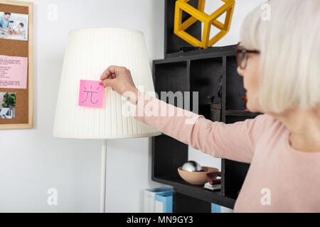 Attraktive, reife Frau, Aufkleber auf die Lampe Stockfoto