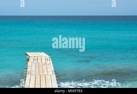 Holzsteg und türkisblauem Wasser am Illetas Strand in Formentera. Balearen. Spanien Stockfoto