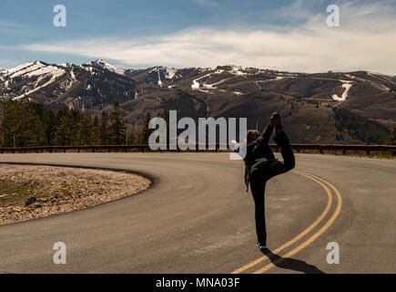 Afrikanische amerikanische Frau Durchführen einer yoga Pose und durch Schmelzen von Schnee auf den Bergen von Deer Valley ski Resorts in Park City, Utah, USA umgeben. Stockfoto