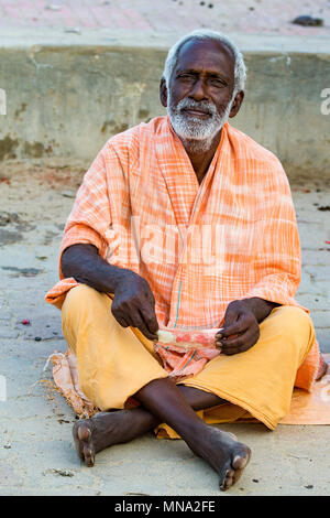 Portrait von nicht identifizierten Sadhus Pilger Devotees, in orange gekleidet, sitzen auf der Straße, auf der Straße und warten auf das Essen. Stockfoto