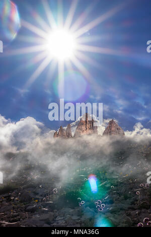 Sun Beam an den Drei Zinnen, einem berühmten Berg Wahrzeichen der Dolomiten, mit wispy Wolken und Sommer Blumen Stockfoto