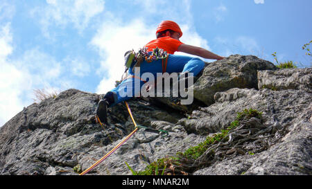 Kletterer in hellen Farben gekleidet auf einem steilen Granit Klettersteig in den Alpen Stockfoto
