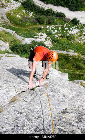 Kletterer in hellen Farben gekleidet auf einem steilen Granit Klettersteig in den Alpen Stockfoto