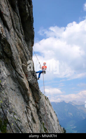 Kletterer in hellen Farben gekleidet auf einem steilen Granit Klettersteig in den Alpen Stockfoto