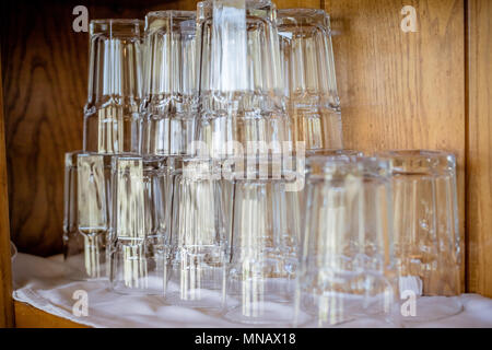 Juce Glas. Close up leere Gläser auf den Showcase in Restaurant, für Esszimmer vorbereiten. Stapel der saubere Gläser. trocken, transparente Gläser stehen in einer Reihe mit der Oberseite nach unten. selektive Fokus Stockfoto