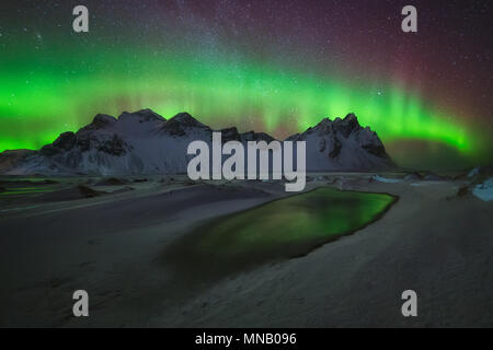 Aurora Borealis grüne Reflexion über das Wasser bei Stokksnes Stockfoto