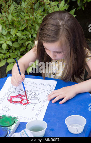Vier Jahre altes Mädchen Malerei Bilder und Muster mit Wasserfarben in Garten, malen Sie auf Händen. Stockfoto