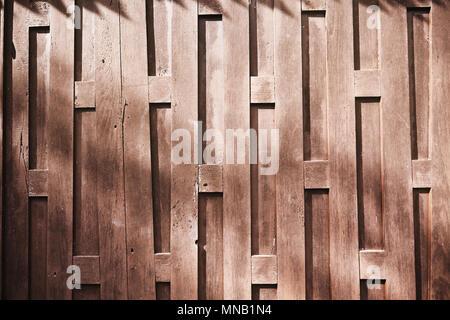 Die Sonne Licht auf die alte hölzerne Wand der traditionellen Haus's Thai mit Einzigartigkeit Muster zeigen den Wald abstrakte Textur Stockfoto