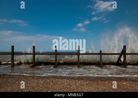 Wellen stürzen gegen einen Breakwater in Norfolk Stockfoto