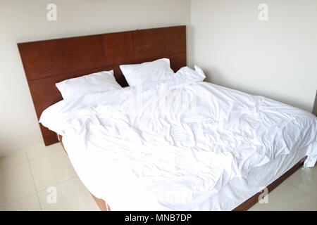 Leere Holz- Bett mit weißer Bettwäsche im Hotel.
