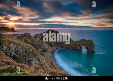 Die Sonne über dem Ärmelkanal an Durdle Door auf der Jurassic Coast in Dorset Stockfoto