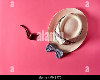 Schön rauchen Rohr auf rosa Hintergrund in der Nähe von Stroh Hut mit Sonnenbrille und Bow Tie liegen Stockfoto