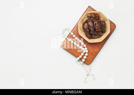 Tabelle Ansicht von oben Luftbild der Dekoration Ramadan Kareem urlaub Hintergrund. Flachbild Datum in Holz Korb mit weiß Rosenkranz & Beleuchtung legen. Das heilige Buch der Stockfoto