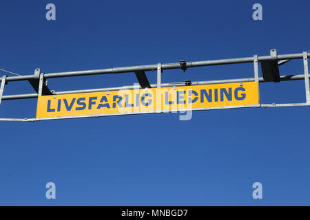 Schwedische Zeichen informiert an einem Bahnübergang über die gefährlich hohe Spannung Oberleitung. Stockfoto