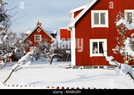 Traditionelles rotes schwedisches Holz- Familienhäusern umgeben von Schnee im Winter Stockfoto