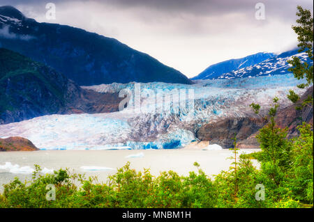 Mendenhall Glaier bei bewölktem Himmel in Tongass National Forest in Alaska. Proglazialen See mit Eisbrocken schwimmend auf der Oberfläche bildet sich an der Gl Stockfoto