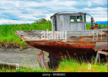 Verfallende abgebrochener Boot in einem Trockendock Rack in einer Wiese vom Wanderweg am Ufer des Kachemak Bucht in Homer, Alaska gesehen sitzen. Stockfoto