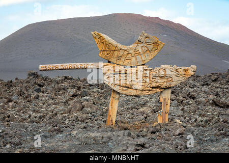 LANZAROTE, KANARISCHE INSELN, SPANIEN: hölzerne Wegweiser zum Feuer Berge am Eingang zum Nationalpark Timanfaya. Stockfoto