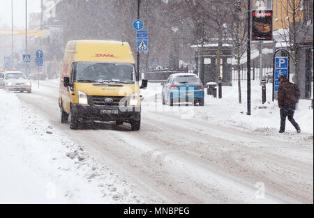 Karlstad, Schweden - Januar 30, 2014: Ein gelber DHL Parcel Delivery van Fahren auf die Straße Ostra Torgatan mit winterlichen Straßenbedingungen in der Stadt cen Stockfoto