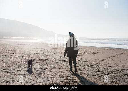 Eine Frau, die zu ihrem Hund auf Croyde Strand Devon Stockfoto