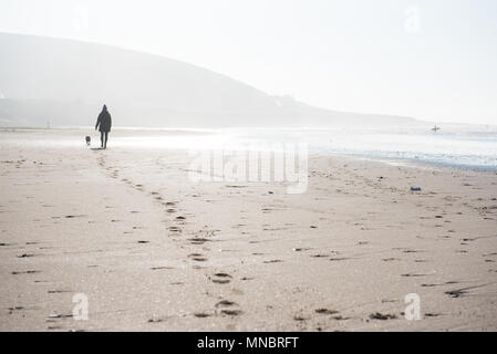 Eine Frau, die zu ihrem Hund auf Croyde Strand Devon Stockfoto