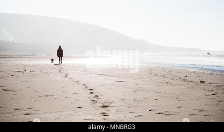 Eine Frau, die zu ihrem Hund auf Croyde Strand Devon Stockfoto