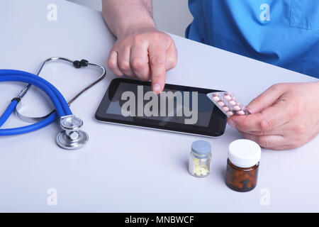Der Arzt hält einen Blister mit Pillen in die Hand und schreibt die Verordnung in den Arbeitsplatz hautnah. Arzneimittel verschreiben, eine zugelassene Apotheke sto Stockfoto